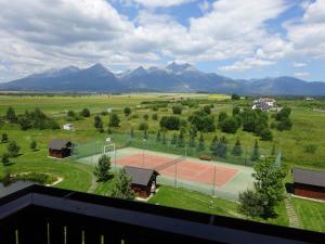 einen Tennisplatz auf einem Feld mit Bergen im Hintergrund in der Unterkunft Sunny apartmány Veľká Lomnica in Veľká Lomnica