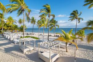 a beach area with chairs, tables and umbrellas at Catalonia Punta Cana - All Inclusive in Punta Cana