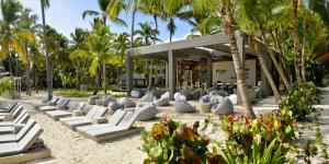 a beach with white lounge chairs and palm trees at Catalonia Punta Cana - All Inclusive in Punta Cana