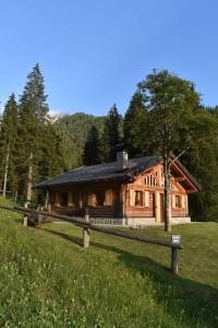una cabaña de madera con una valla delante en Chalet Brenta Dolomites, en Madonna di Campiglio