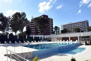 a swimming pool with lounge chairs and a building at Hotel Olimpic in Jupiter