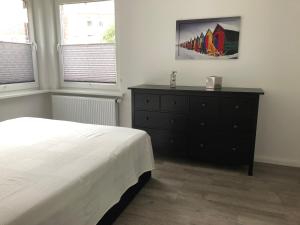 een slaapkamer met een bed, een dressoir en 2 ramen bij Eg in Wilhelmshaven