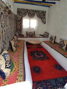 a living room with a couch and a red rug at Maison d'hôtes "Abou-Hachem" in Melaah