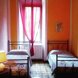 a bedroom with two beds and a window with red curtains at Ca Giulietto Antico Casale in Lunigiana in Pontremoli