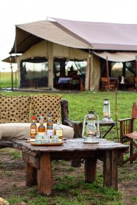 una mesa de madera con botellas de alcohol. en Pumzika Luxury Safari Camp, en Banagi