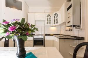 a kitchen with white cabinets and a vase of flowers on a table at Anna apartman in Szeged