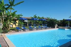 una piscina con sillas y sombrillas azules en Roy House, en Alghero