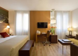 ミラノにあるスターホテルズ リッツのベッドとデスクが備わるホテルルームです。