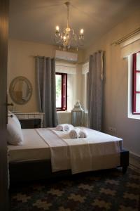una camera da letto con un grande letto bianco e un lampadario a braccio di Traditional house of 1898 in the heart of old town of Nafplio a Nauplia