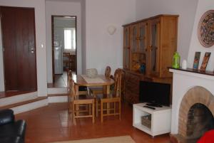 a living room with a table and a tv at Casa Sobral in Vila Nova de Milfontes