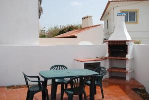 a patio with a table and chairs and a fireplace at Casa Sobral in Vila Nova de Milfontes