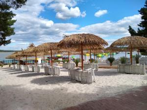 a row of chairs under straw umbrellas on a beach at Apartmán v Zátiší in Staré Splavy
