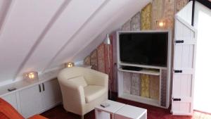 a living room with a television and a chair at Noordwester 45 in Den Burg