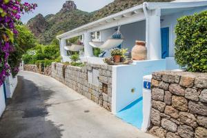 a white house with a stone wall and a street at La Sirena in Panarea