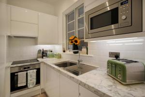 a white kitchen with a sink and a microwave at Macatsim Seaview Sunset in Margate