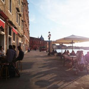 a group of people sitting at tables on a street at San Mark's basin best view in Venice
