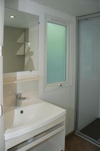 a white bathroom with a sink and a mirror at Camping Listro in Castiglione del Lago