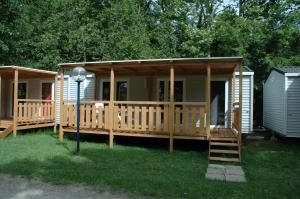 a large wooden cabin with a porch and a staircase at Camping Listro in Castiglione del Lago