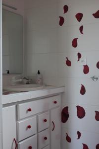 a bathroom with a sink and red hearts on the wall at Au p'tit Mont in Ardevon