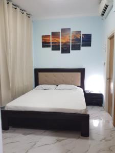 uma cama num quarto com três pinturas na parede em Ashdod Beach Hotel em Ashdod