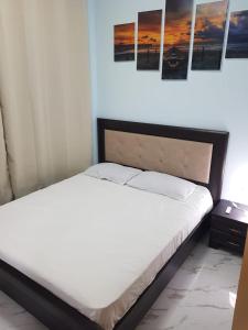 um quarto com uma cama branca e quadros na parede em Ashdod Beach Hotel em Ashdod