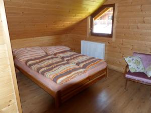 Bett in einem Blockhaus mit Fenster in der Unterkunft Chatka u šindelára in Liptovský Mikuláš