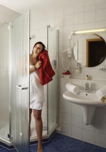 a woman standing in a bathroom holding a towel at Hotel Drei Konige in Schramberg