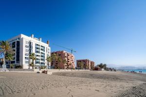 Blick auf einen Strand mit Gebäuden und Palmen in der Unterkunft Gran vivienda de lujo frente al mar in Málaga