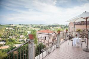 einen Balkon mit einem Tisch und einem Sonnenschirm in der Unterkunft Dimora Il Palazzetto in Cugnoli