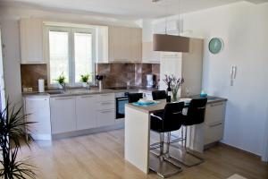 a kitchen with white cabinets and black bar stools at Apartmani Žorić in Punat