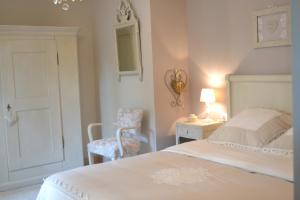 a white bedroom with a bed and a chair at Gîte La Cour Anglaise in Plobsheim