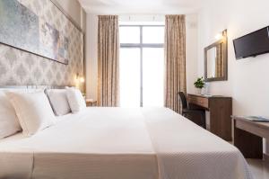 una camera d'albergo con un grande letto bianco e una scrivania di Alexandra Hotel a San Giuliano