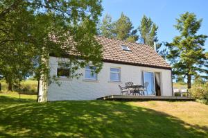 ein weißes Haus mit einem Picknicktisch davor in der Unterkunft Birch Cottage in Blairmore
