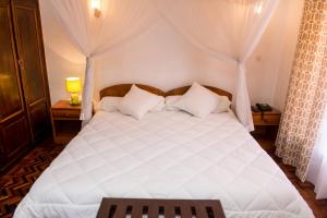 - une chambre avec un grand lit blanc et des rideaux dans l'établissement Ivotel, à Antananarivo