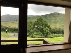 a window with a view of a field and mountains at Kylemore Pass Hotel in Letterfrack