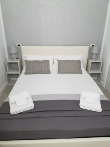 ein weißes Bett mit Kissen und zwei Nachttischen in der Unterkunft Summer Rooms in Margherita di Savoia