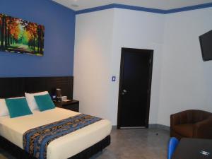 a bedroom with a bed and a couch and a chair at Hotel Del Centro in Guayaquil