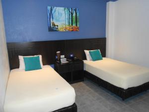 2 Betten in einem Zimmer mit blauen Wänden in der Unterkunft Hotel Del Centro in Guayaquil