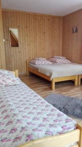 two beds in a room with wooden walls at Pokoje Goscinne U Janki in Murzasichle