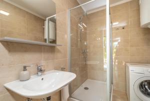ein Badezimmer mit einem Waschbecken, einer Dusche und einer Waschmaschine in der Unterkunft Kiwi in Trogir
