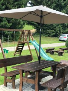 a picnic table with an umbrella and a slide at Vila Jensen in Harrachov