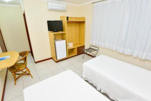a hotel room with a television and a bed at Hotel Plaza Mar in Vila Velha