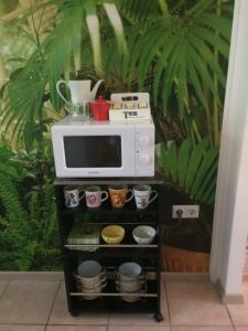 a microwave on a shelf with cups and bowls at Ifjúság Nyaraló in Poroszló