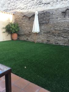 a patio with an umbrella and a green lawn at Apartamentos Rurales el Trillo in Malpartida de Plasencia