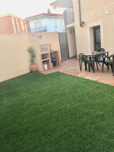 un patio trasero con césped verde, mesa y sillas en Apartamentos Rurales el Trillo en Malpartida de Plasencia