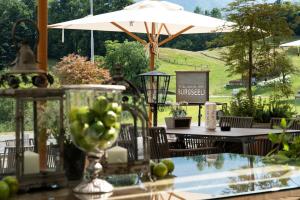 una mesa con sombrilla y una mesa con un bol de fruta en Hotel-Restaurant Burgseeli, en Goldswil