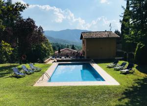 a swimming pool in a yard with chairs and a house at Hostal de la Gloria in Viladrau