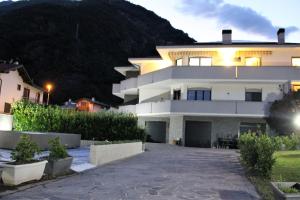 duży biały dom z górą w tle w obiekcie AFFITTACAMERE VALCHIAVENNA - Foresteria Lombarda con PARCHEGGIO PRIVATO SUL POSTO! Apprezzata Gestione Familiare dal 2012, Qualità-Prezzo TOP! "Guest-House with PRIVATE PARKING ON SITE! Appreciated Family Management since 2012, Quality-Price TOP!" w mieście Chiavenna