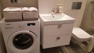 łazienka z pralką i umywalką w obiekcie Apartament Morski przy Latarni w Darłówku