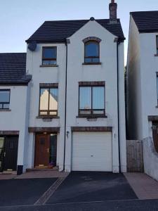 a white house with a garage at Spire View Townhouse in Ballycastle